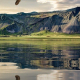 An eagle flies above a large lake with a low mountain in the background