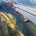 An airplane wing reaches out over a dramatic, mountainous landscape below