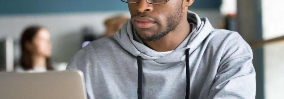 A man sits in a café working on a laptop computer