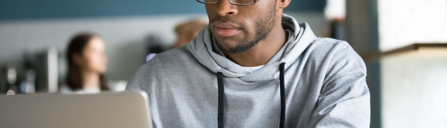 A man sits in a café working on a laptop computer